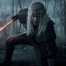 liam hemsworth as geralt of rivia wielding a red glowing sword while crouching down in the witcher season 4
