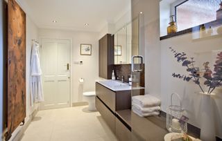 luxury spa style bathroom with white tiles, wood storage and copper radiator