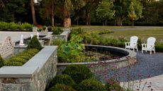 A sprawling garden with a curved pond water feature and a long fountain