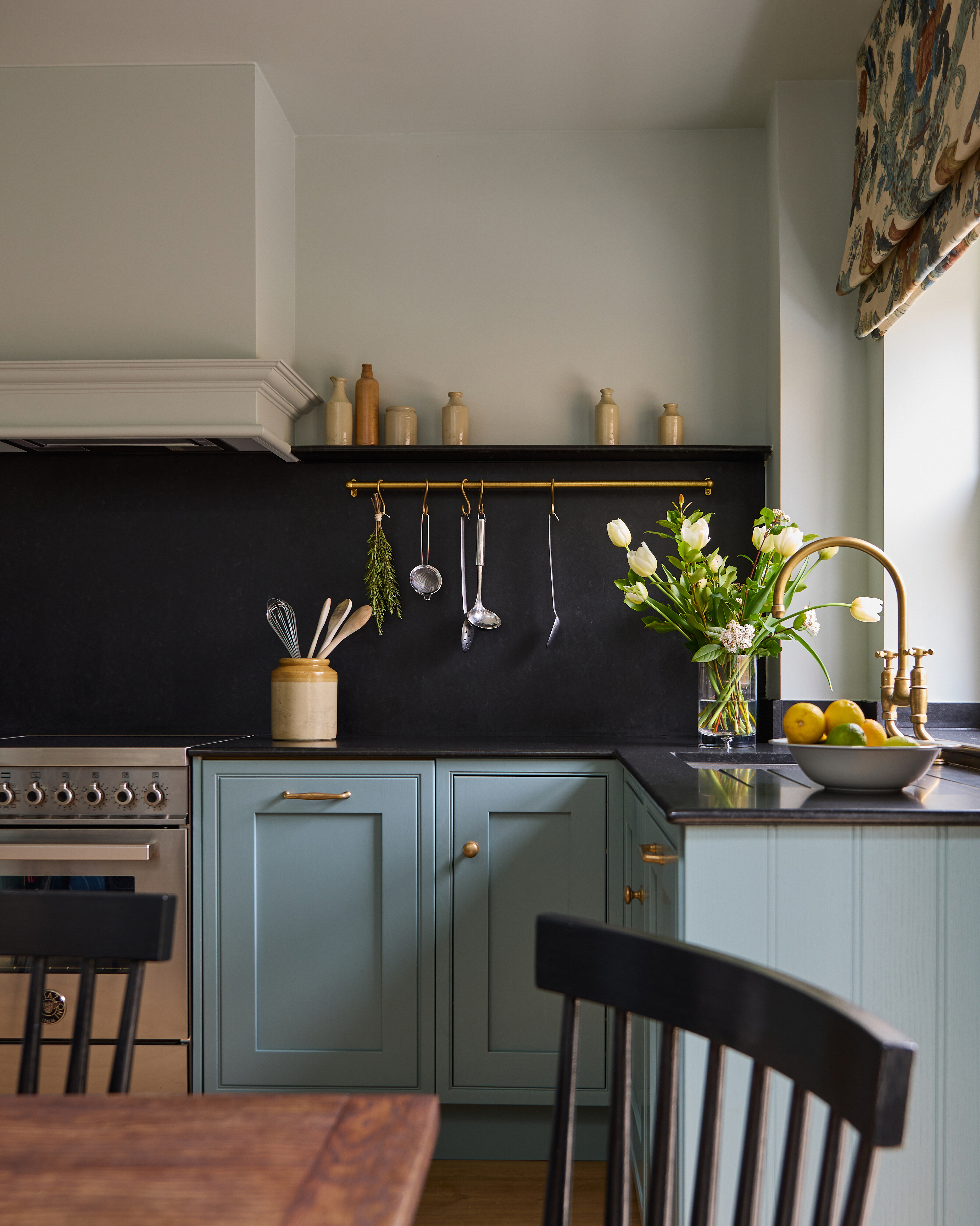 blue kitchen cabinets with black counters and backsplash and gold hardware details