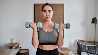 Woman performs biceps curl with dumbbells in a home