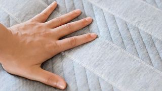 Hand resting on the cover of the Leesa Studio mattress