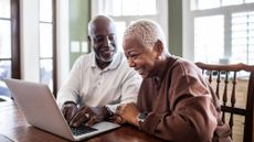 Happy senior couple using laptop at home 