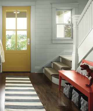 country style entrance with yellow door, mudroom style benches by staircase - Benjamin Moore