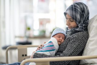 A woman cuddling her newborn baby. 