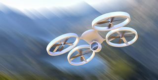 A white drone in flight in front of a blurred background