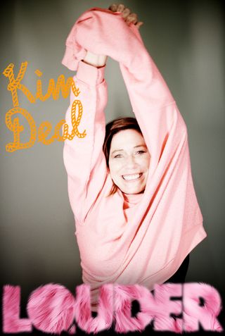 Kim Deal on the cover of Louder posing in a pink sweater