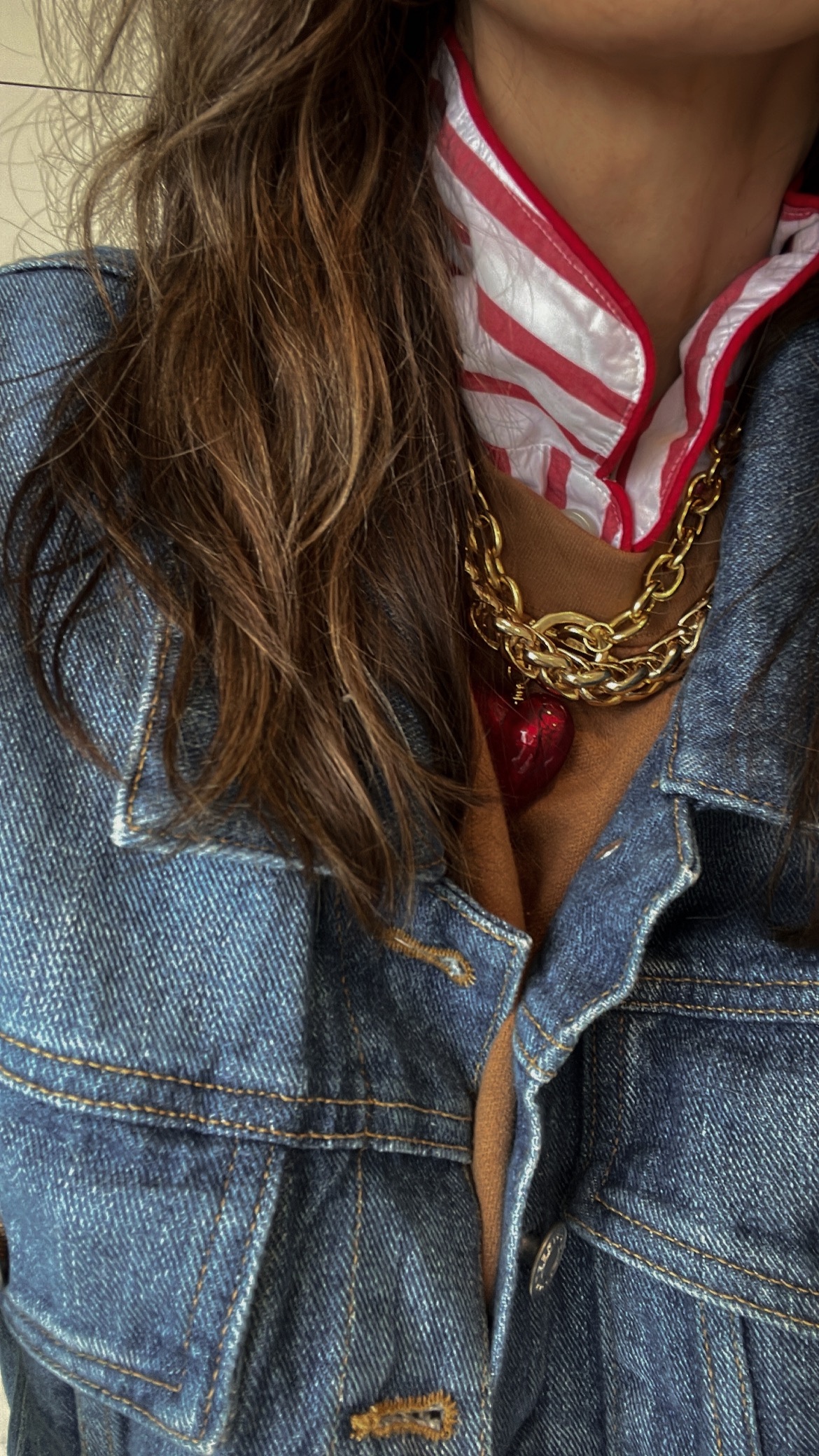 Larissa Mills in a red and white striped pajama top, jean jacket, brown sweater, and gold chain necklace