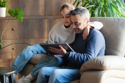 Father and child daughter trying a mobile application using digital tablet at home