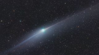 A green comet in space with two long tails of light stretching in opposite directions