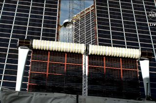 A new International Space Station (ISS) Roll-Out Solar Array (iROSA) unfurls in front of the legacy 4A solar array wing, augmenting the power for the orbiting complex.