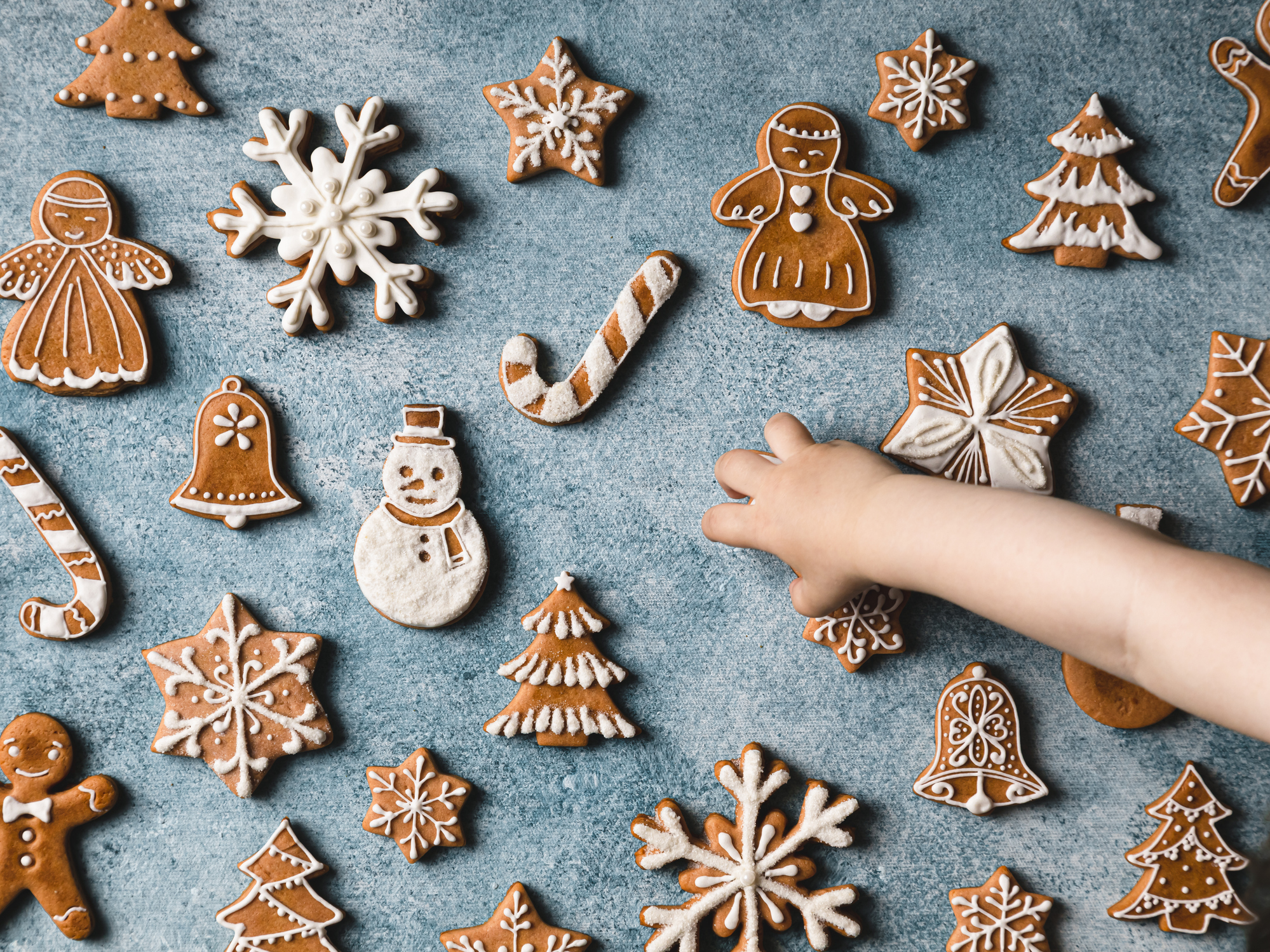 Ein Kind streckt die Hand nach Weihnachtssüßigkeiten aus