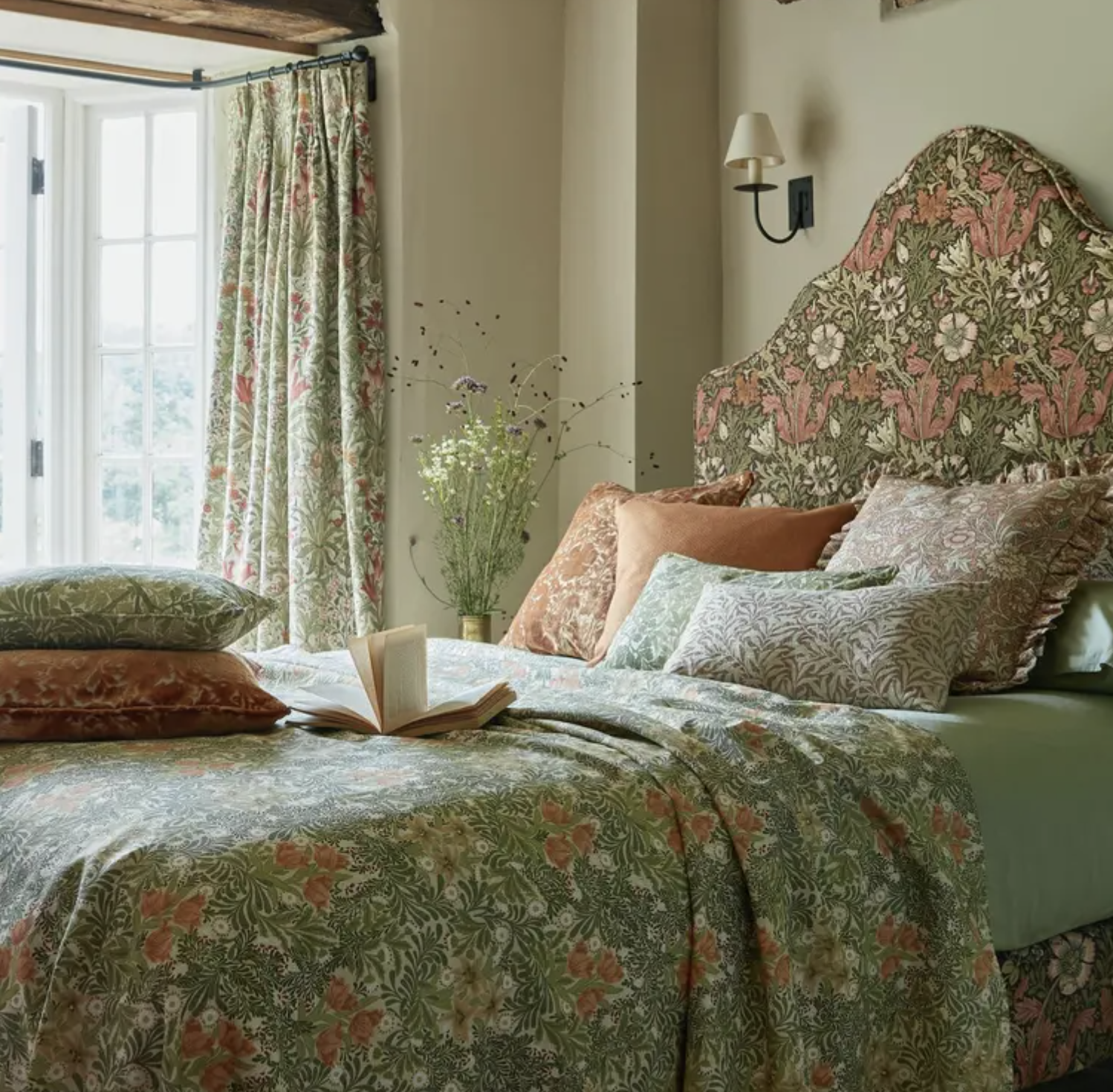 bed in william morris print with green and orange cushions