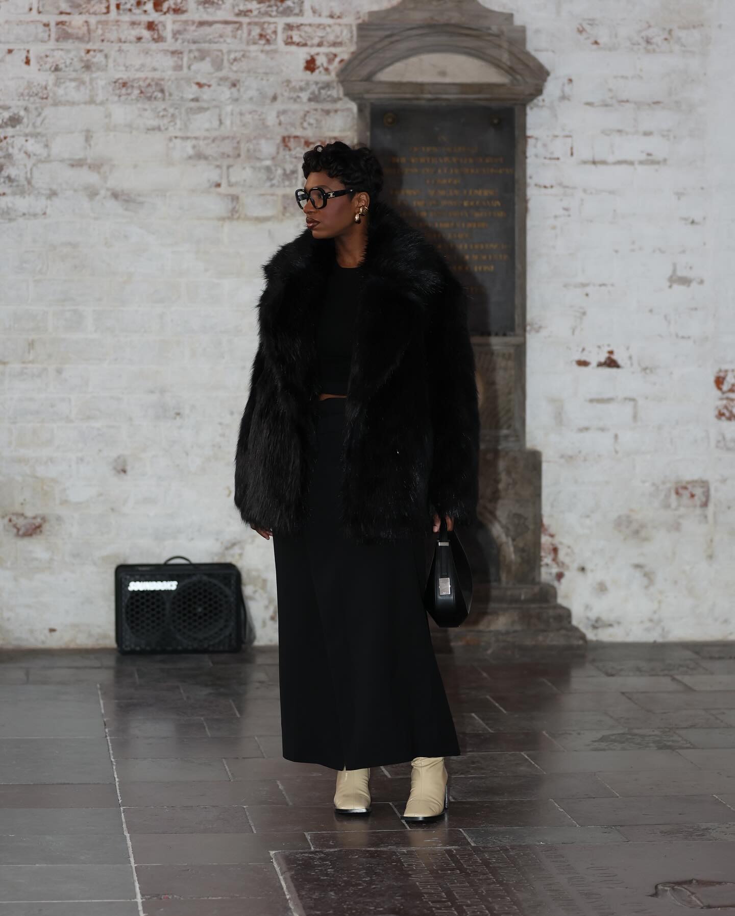 @thevisuelofgrace wearing a long coat with square-toe tan boots.