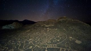 lines and circles carved into a rock, seen under a starry night sky