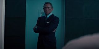 Daniel Craig dressed in a black suit with his arms folded in No Time To Die.