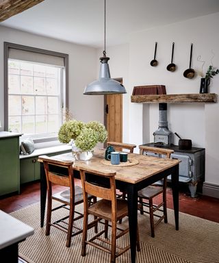 kitchen diner with window seat, terracotta floor tiles and wooden table and chairs and stove