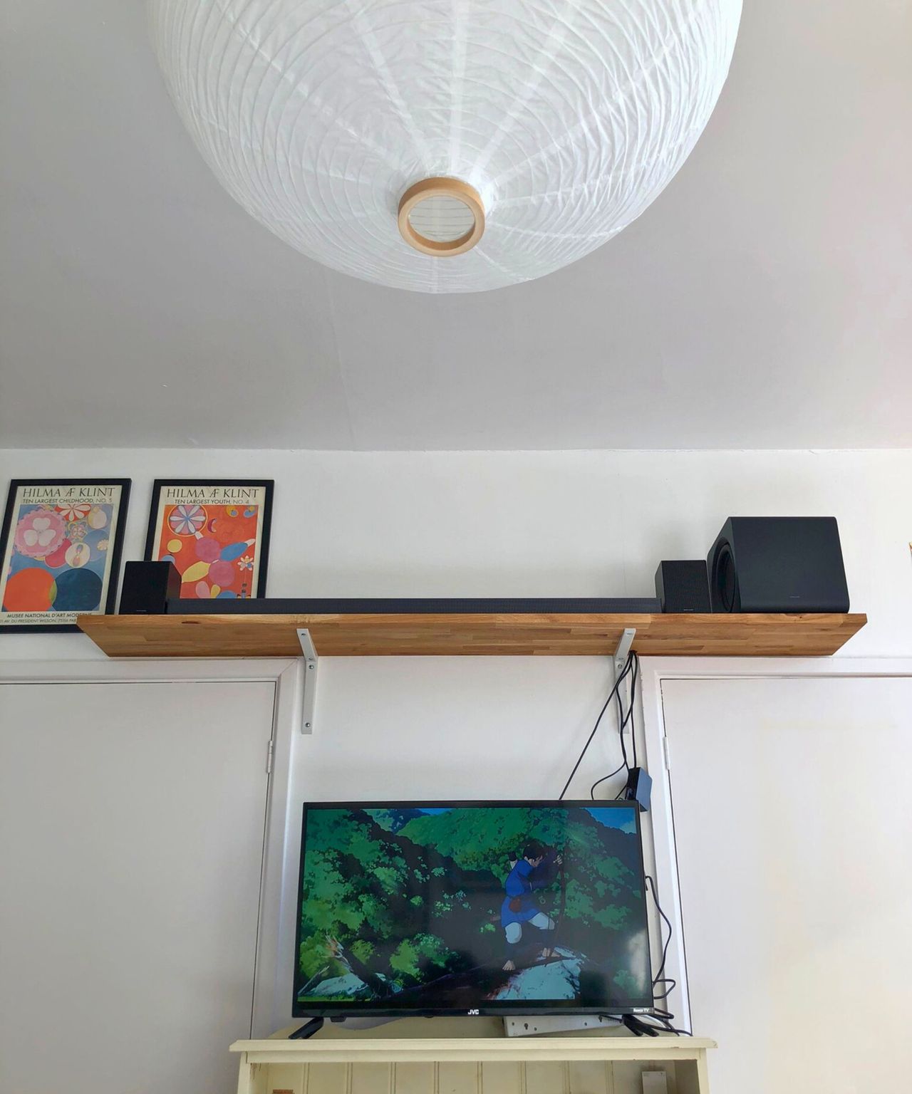 Samsung HW-QS750F soundbar on wooden shelf in Dan Fauzi's home, above TV showing Princess Mononoke and with two art prints pictured to the left.