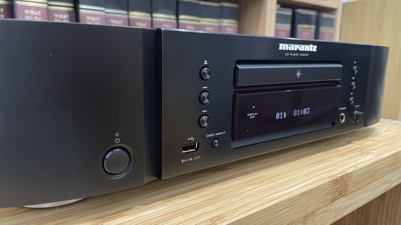 Close up of buttons on Marantz CD6007 on wooden rack with magazines in background