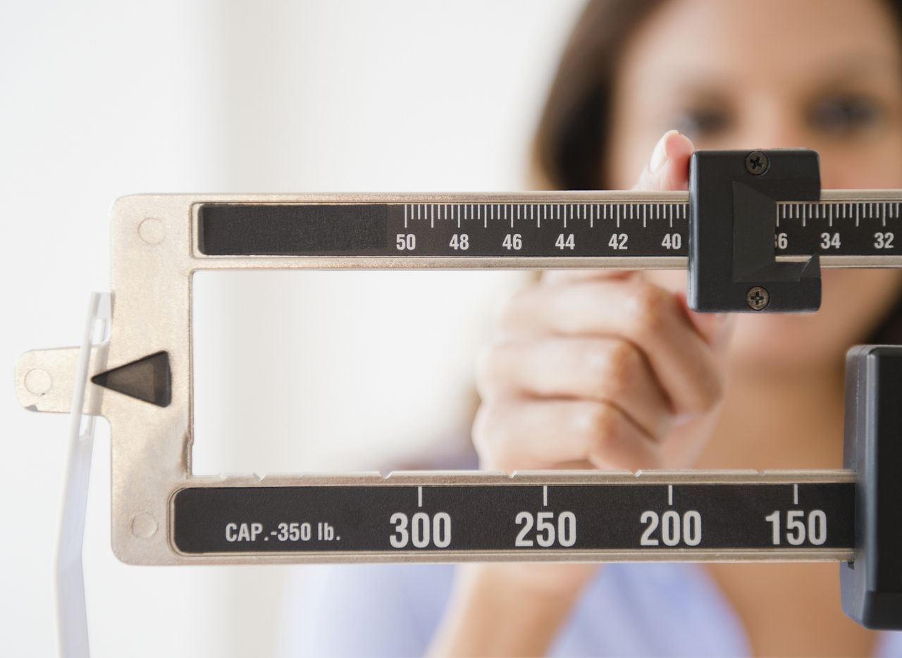 Woman using a scale to weigh herself.