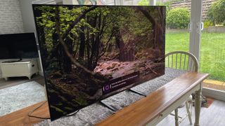 Samsung S90C OLED TV puisella pöydällä ulkoikkunan edessä