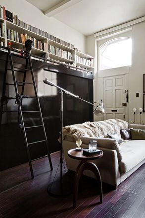 Room with black sliding doors, library on the mezzanine level is accessed by a ladder
