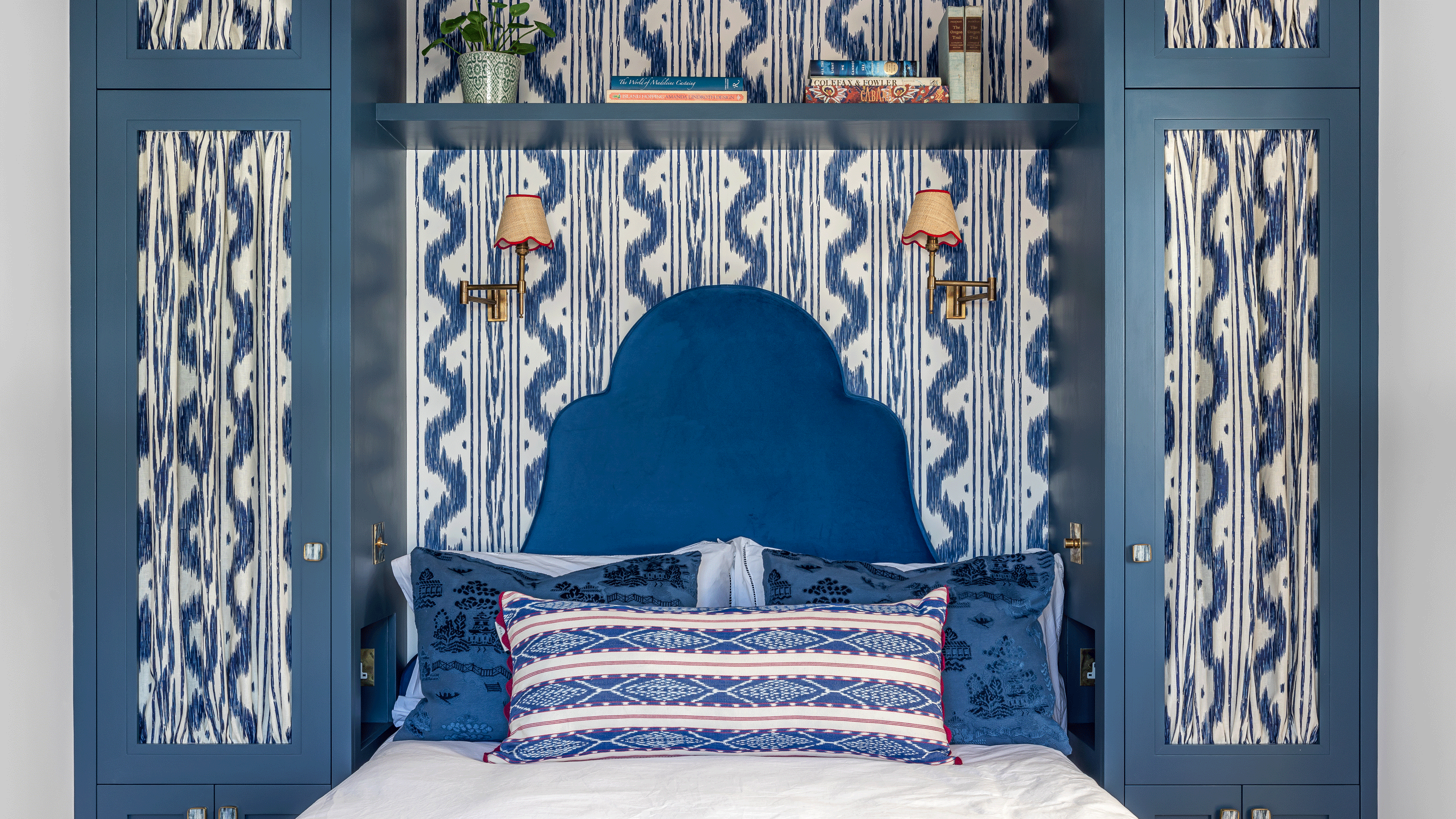 Navy upholstered bed with navy patterned fabric and wallpaper by Barlow & Barlow