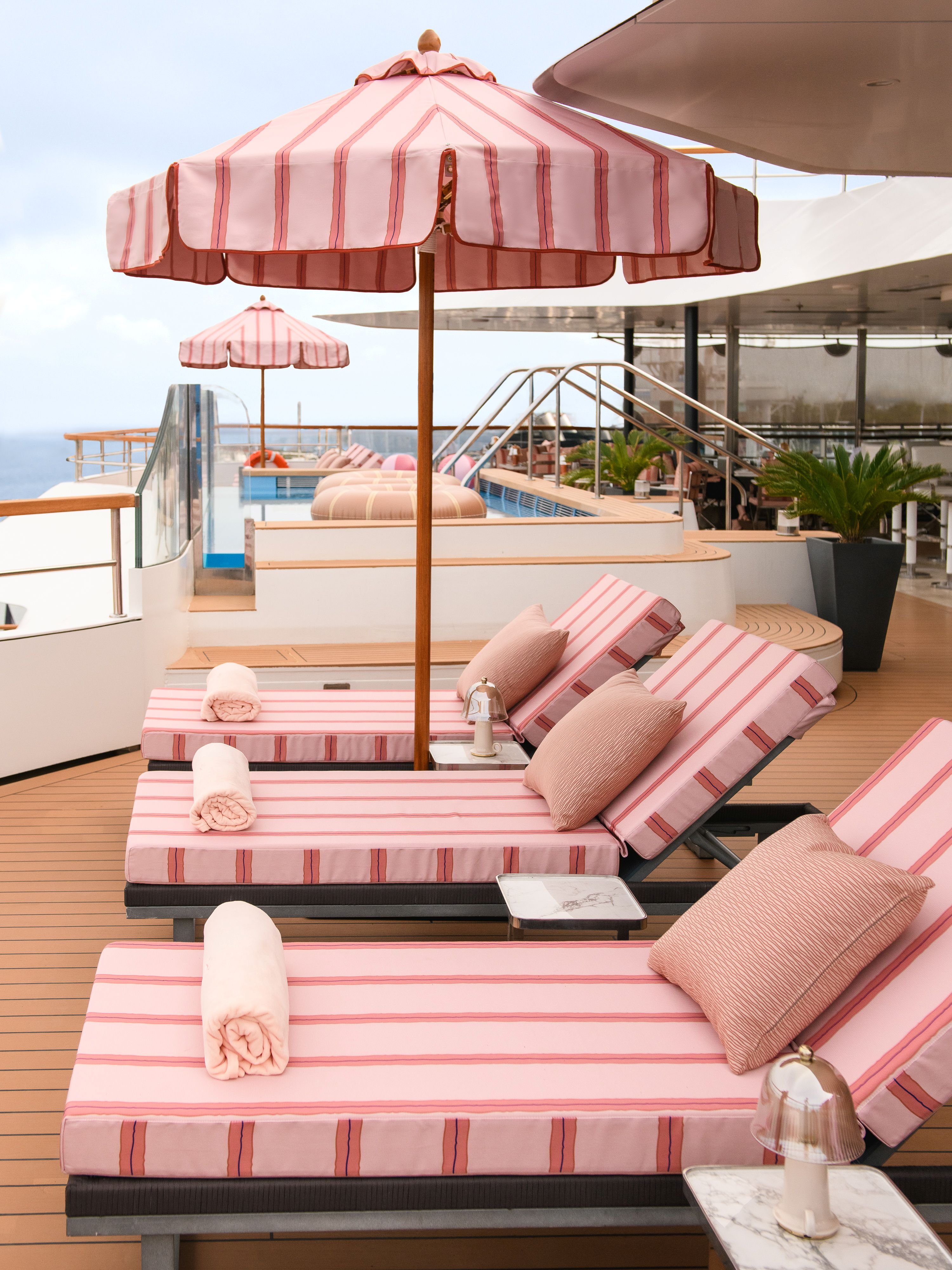 view of a colourful outdoor terrace with pink sunbeds and fine porcelain pieces