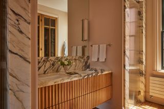 A bathroom with a marble countertop and walls, and a ribbed vanity