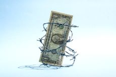 $1 US dollar banknote in barbed wire on light blue background