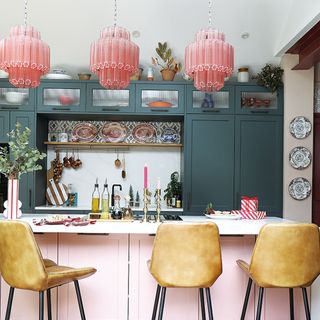 green kitchen with pink island and leather bar stools