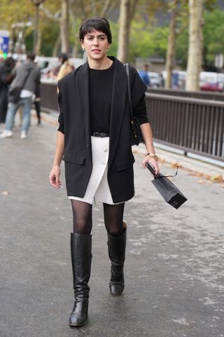 A woman wearing a monochrome look with knee high boots