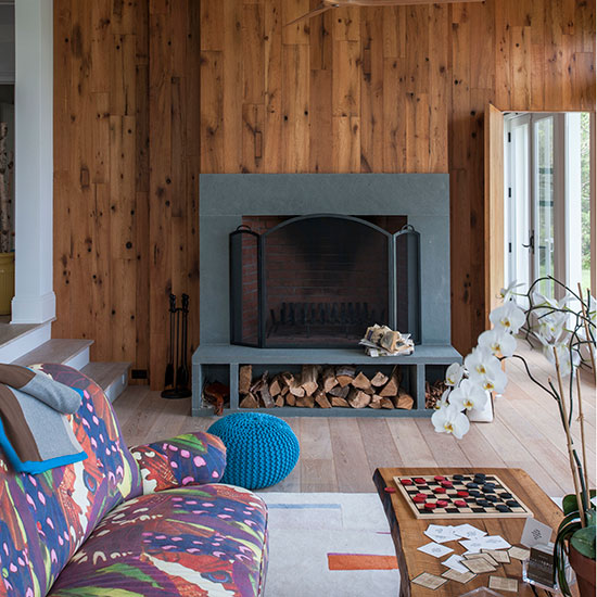 living room with grey fire place and wooden wall
