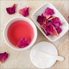 A tray displaying rosewater and rose petals to illustrate a guide to rosewater for face