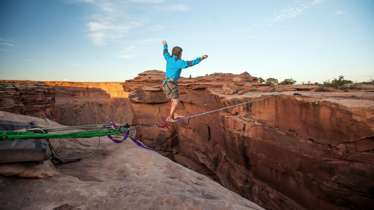 Guy walking on a line over a canyon in Moab