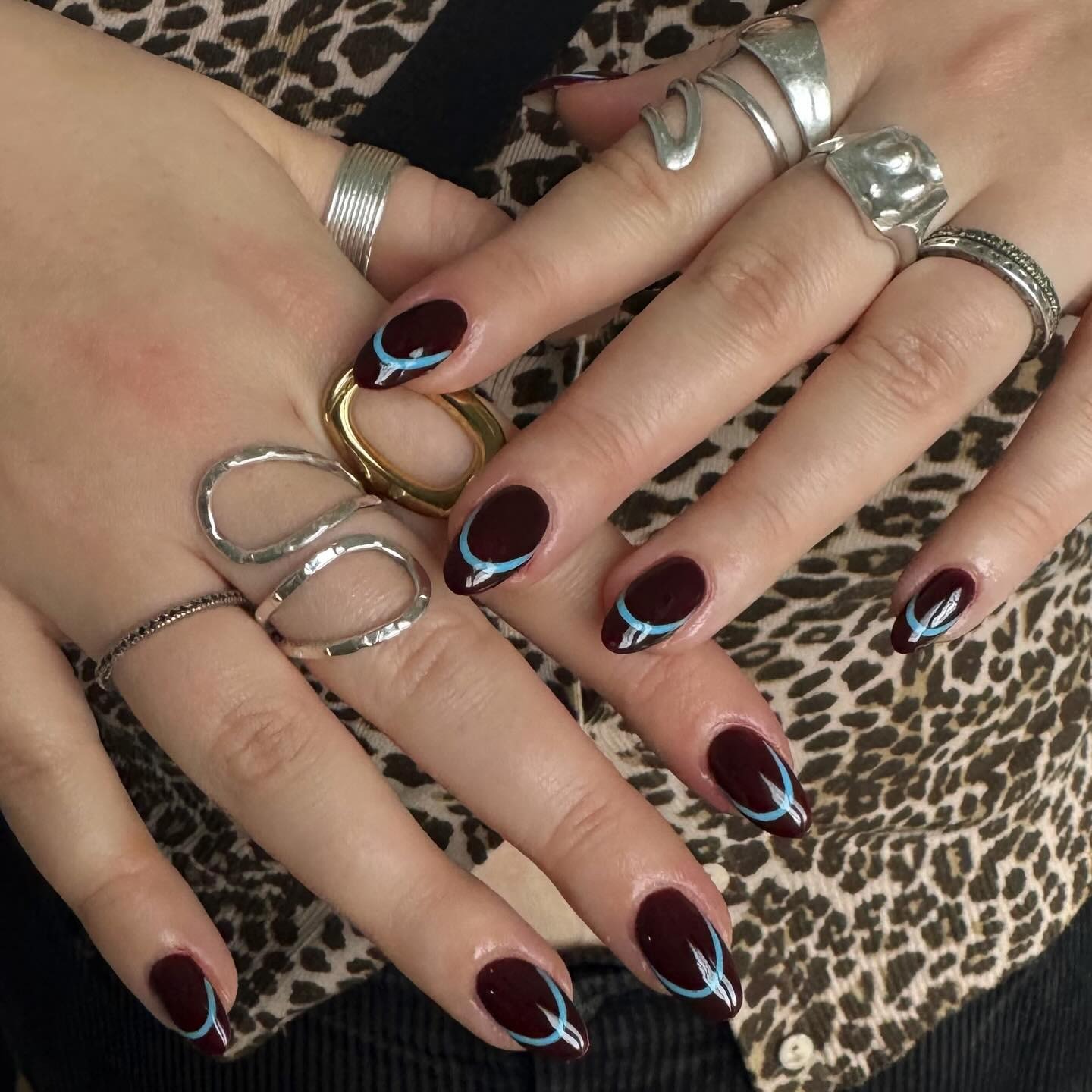An image of dark cherry nails with turquoise accents.