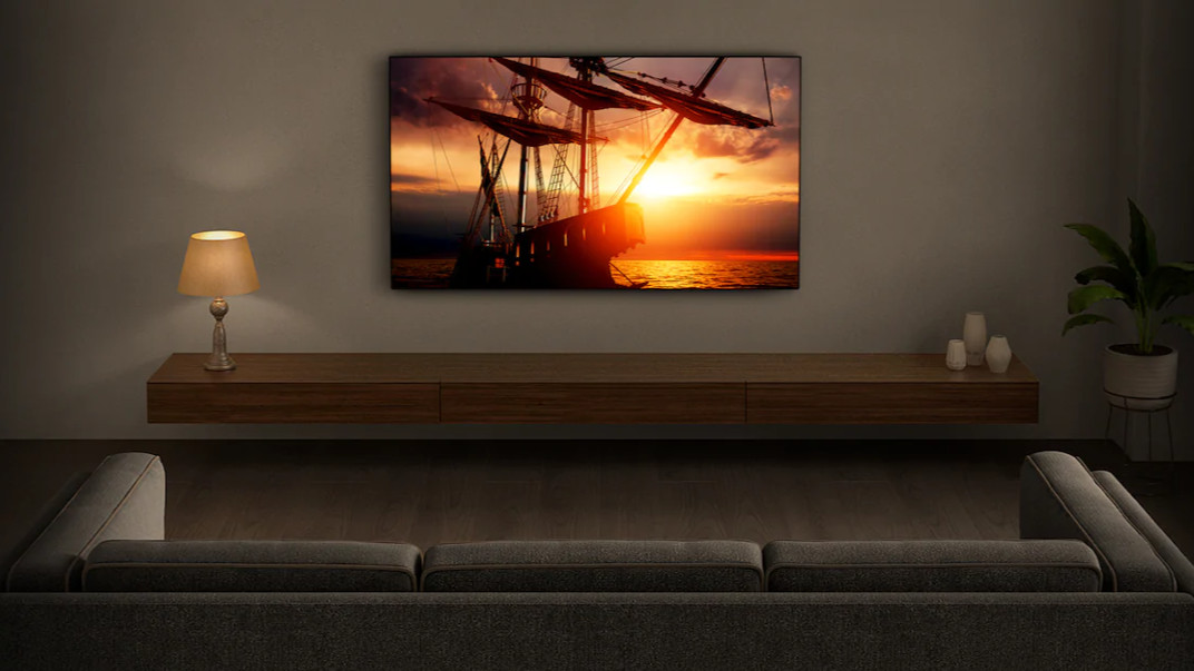 The Sony X90J TV pictured on a grey wall displaying a sunset scene