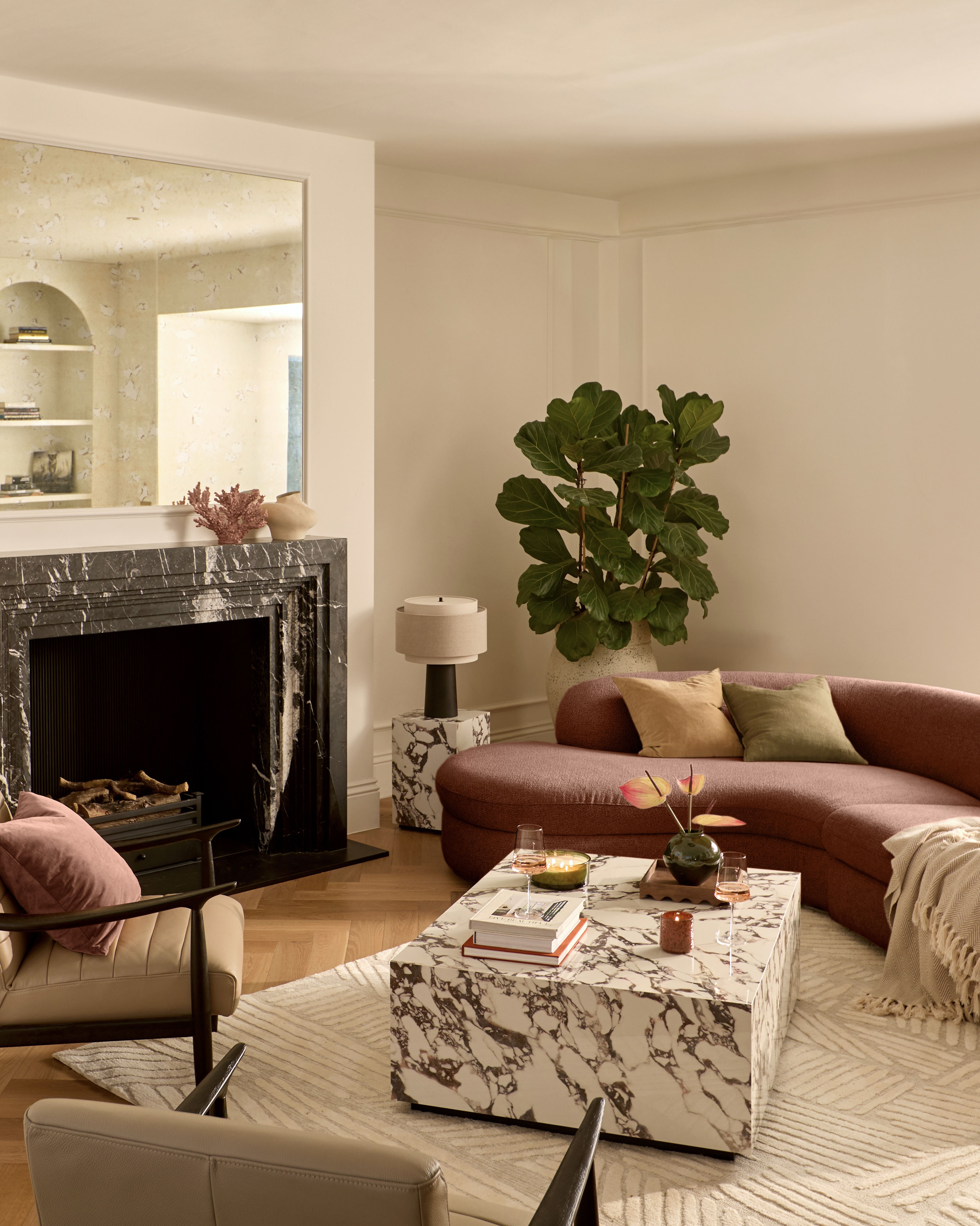 A peige sofa in a contemporary living room with marble coffee and side tables