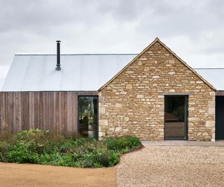 exterior of barn conversion with metal roof, timber cladding and stone