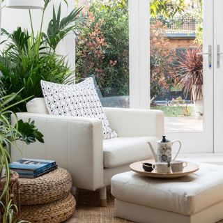 A white conservatory with house plants and leather arm chair