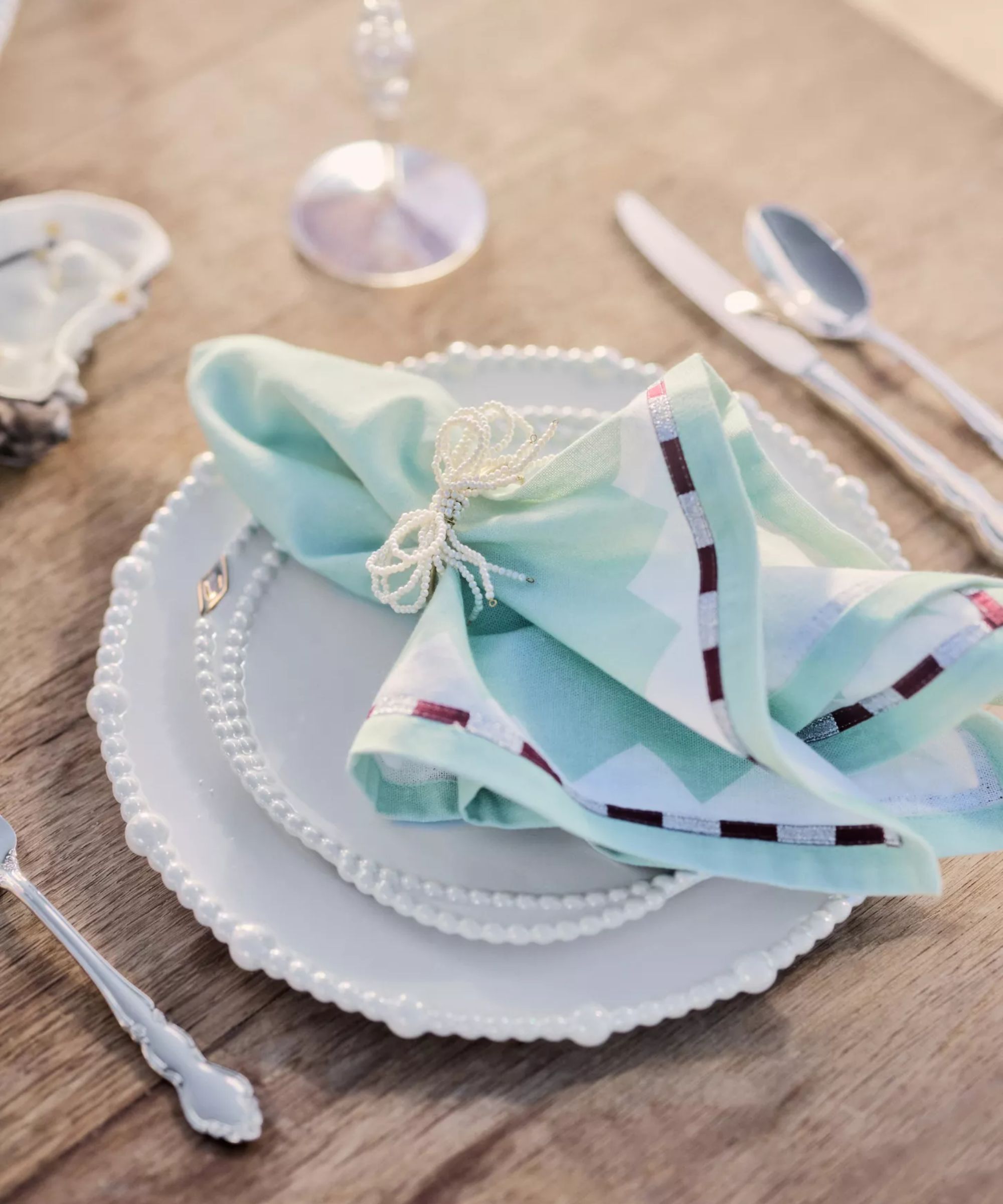 White pearl plates with ocean blue napkins and pearl bow napkin rings