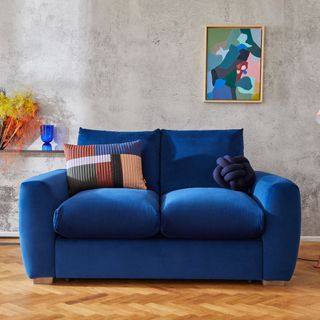 living room with frame on wall and blue couch on wooden floor