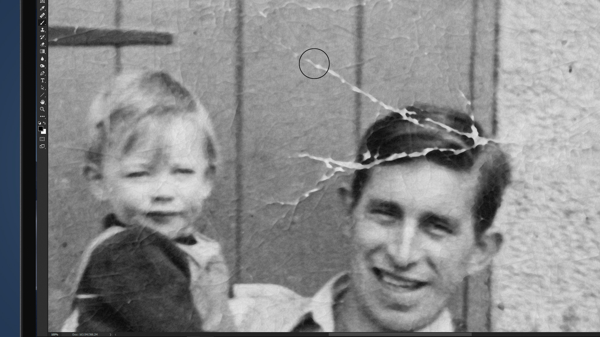 A laptop screen showing an old photo being restored in Photoshop