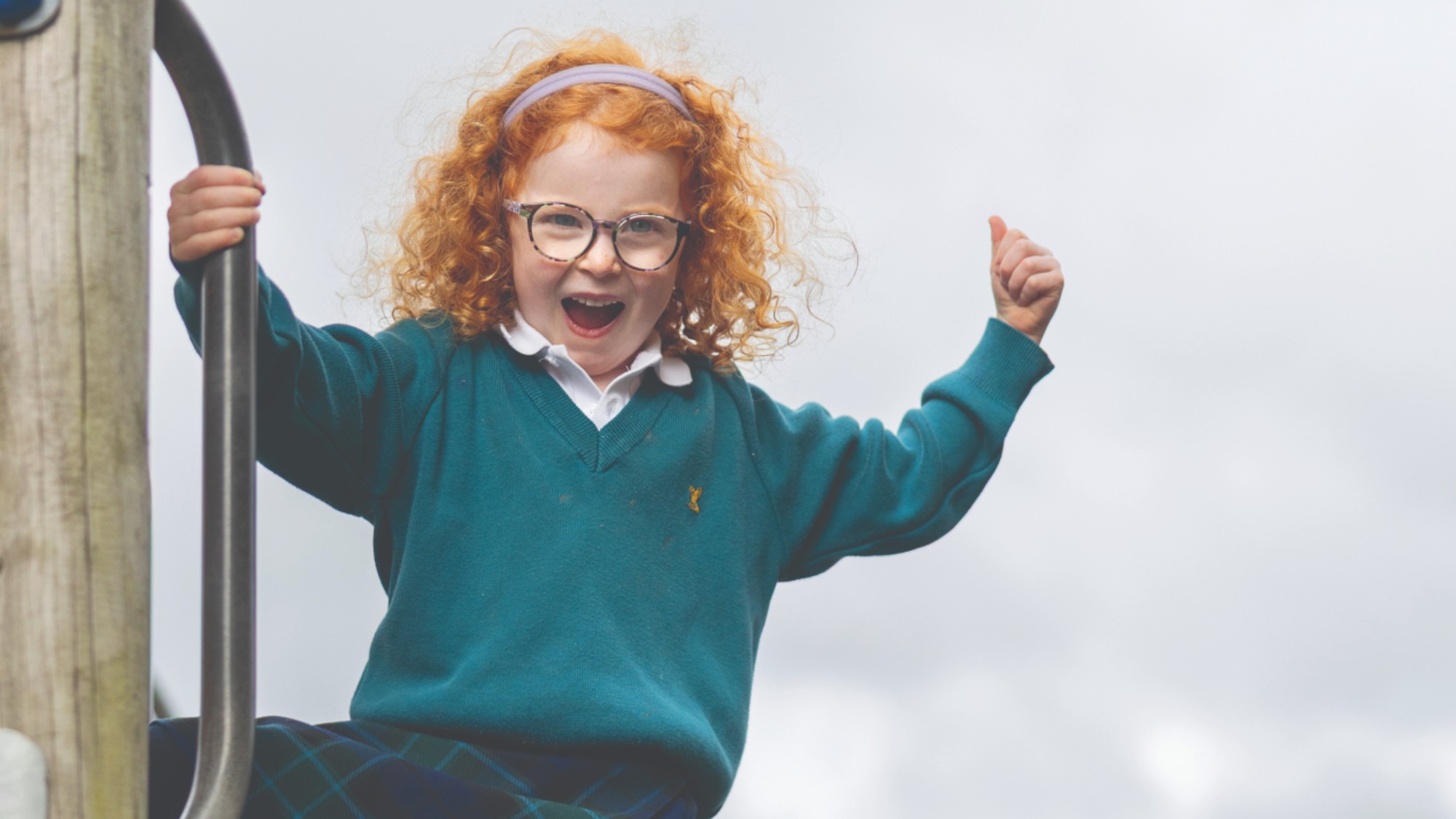 A girl in school uniform stands on play equipment