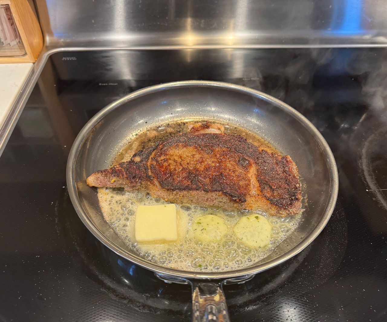 The Hestan NanoBond Skillet with a cooked steak inside, with three pats of melting butter