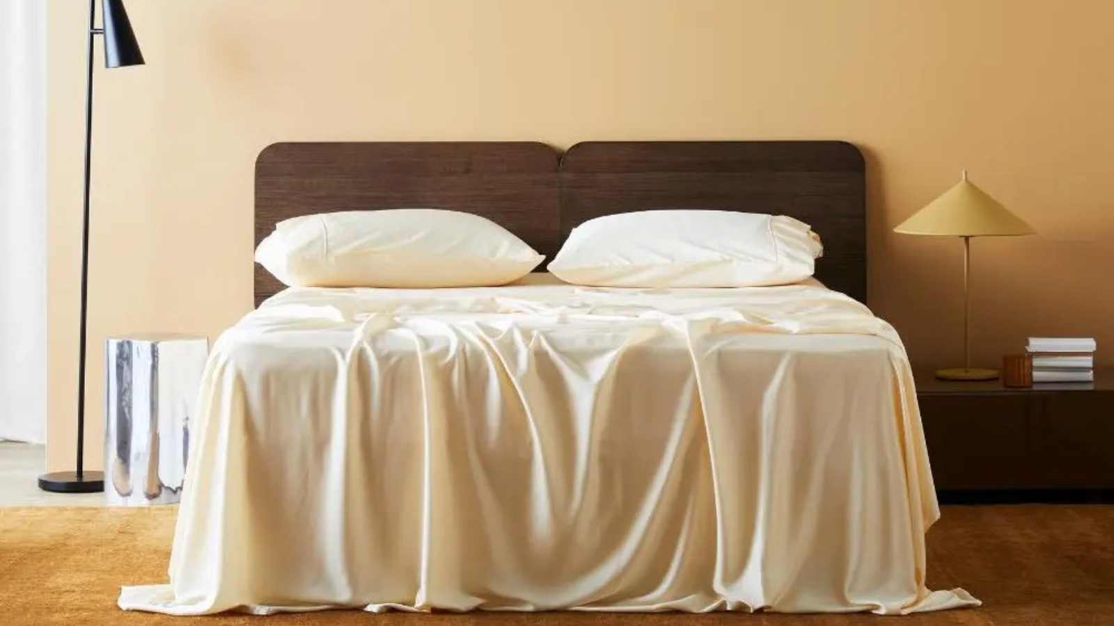 a minimalist room with butter yellow bedding, a wood headboard, a floor lamp, and a table lamp