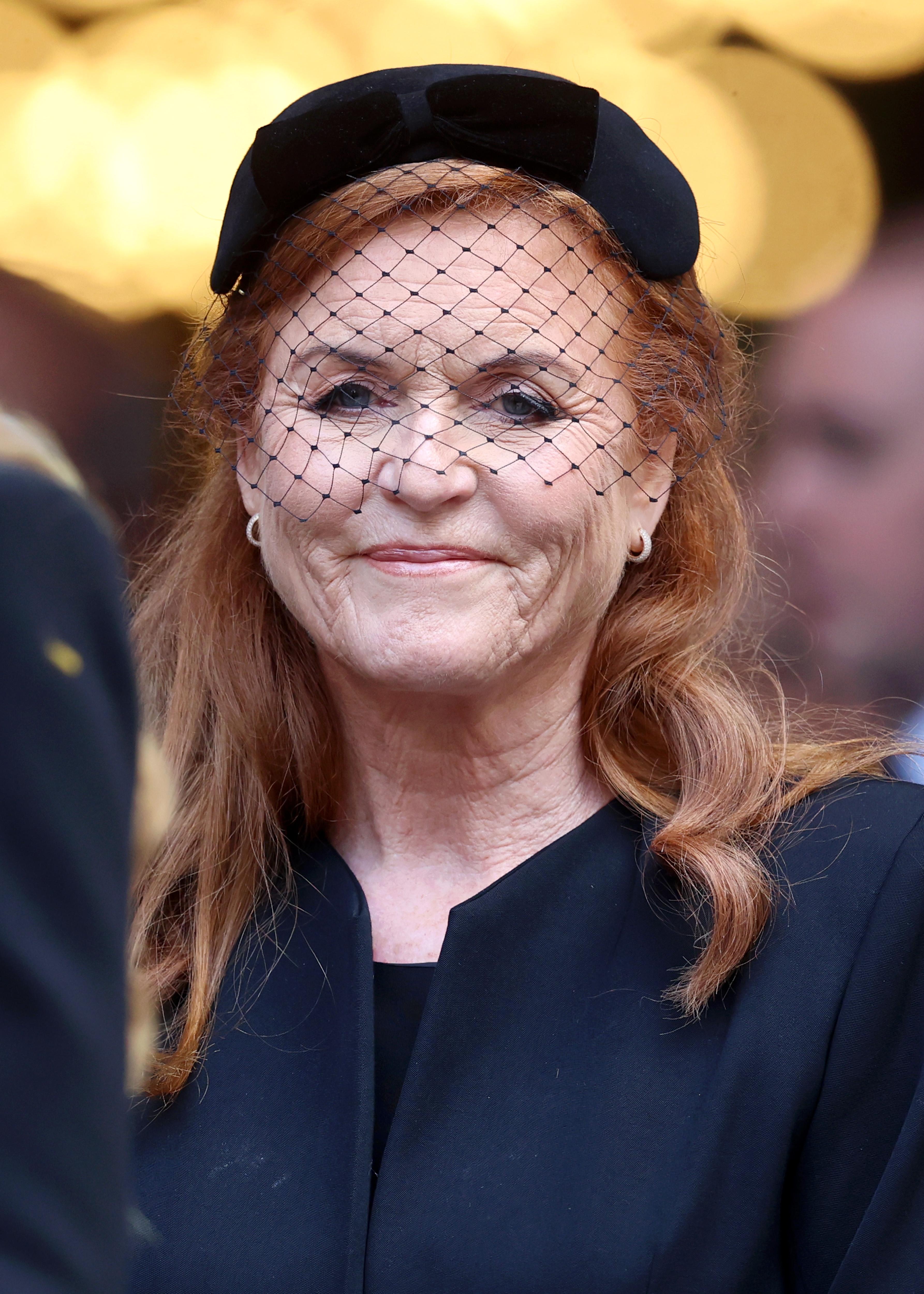 Sarah Ferguson wearing a black hat and coat smiling