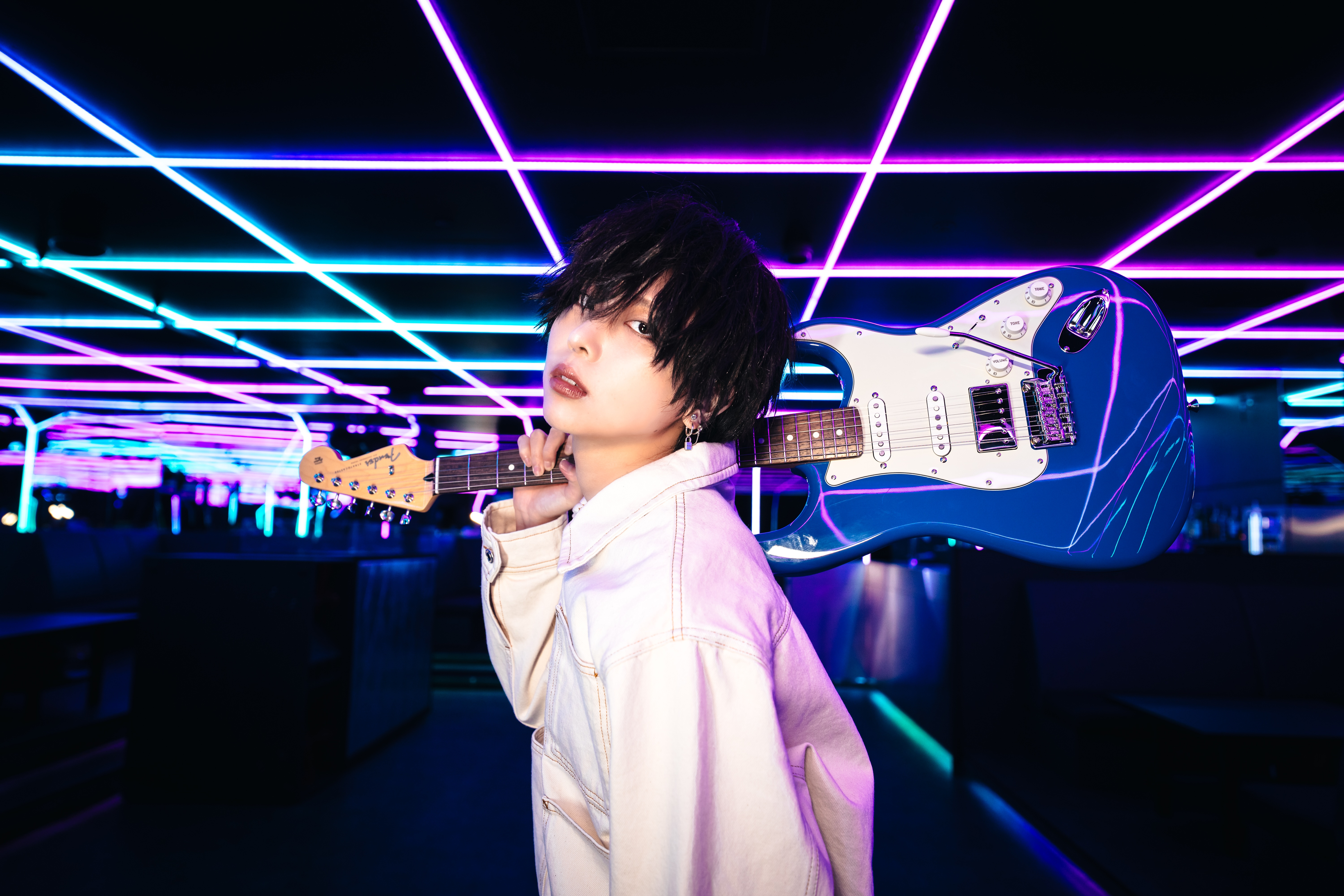 Otoha holding a Fender Strat against a futuristic, neon-lit backdrop