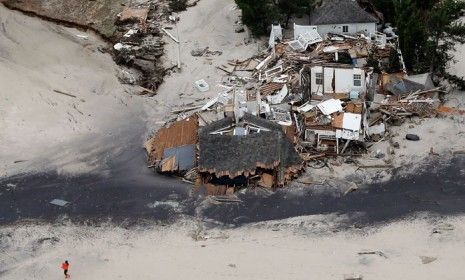 A woman walks on the beach in Mantokloking, New Jersey, past homes destroyed by Hurricane Sandy, on Oct. 31.