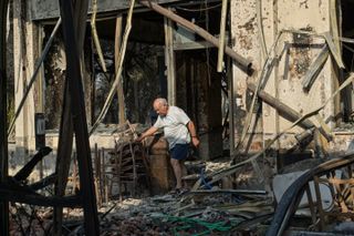 A man inspects his fire damaged home in northern Athens